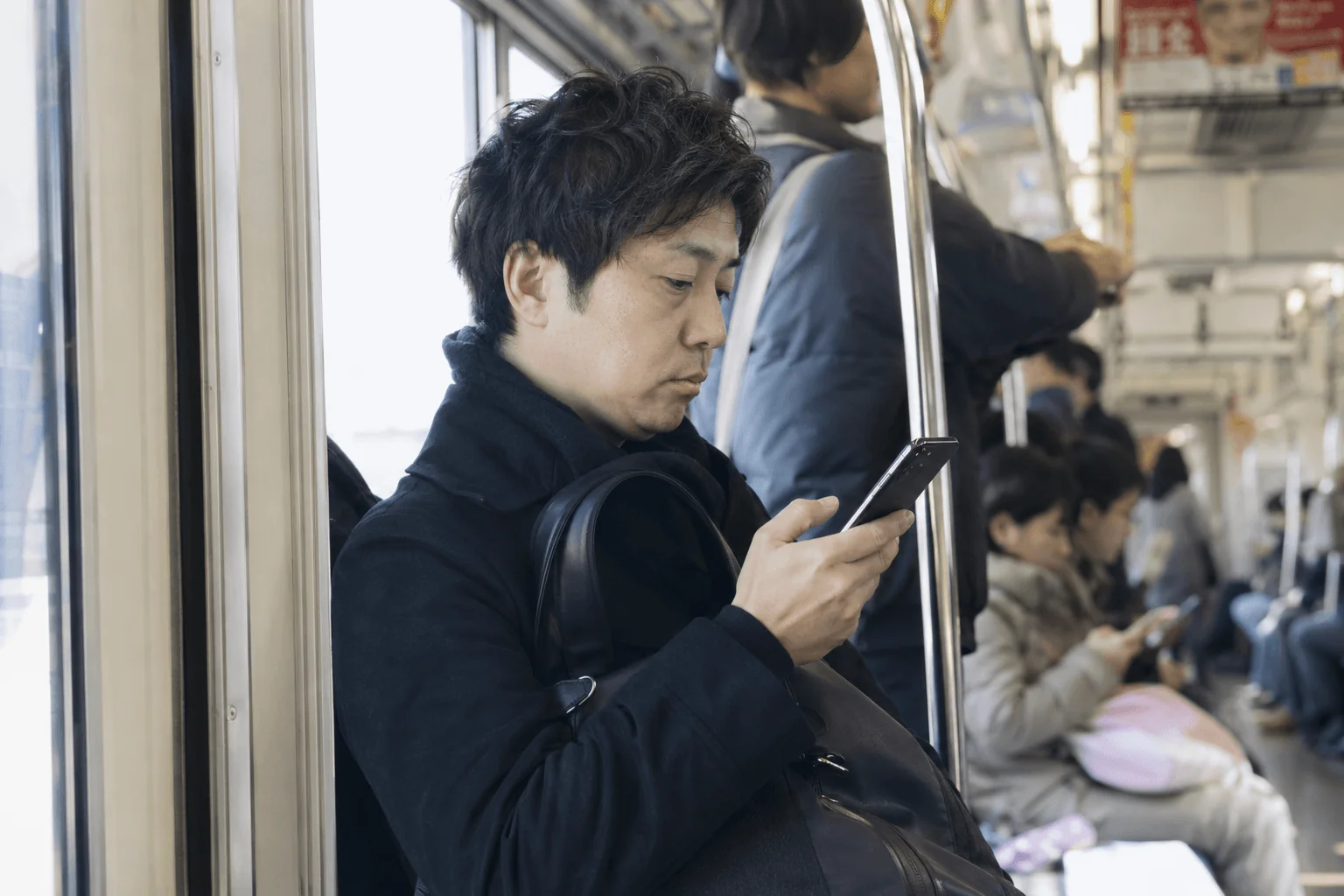 A commuter on a Tokyo train scanning his phone — attention decided in a split second