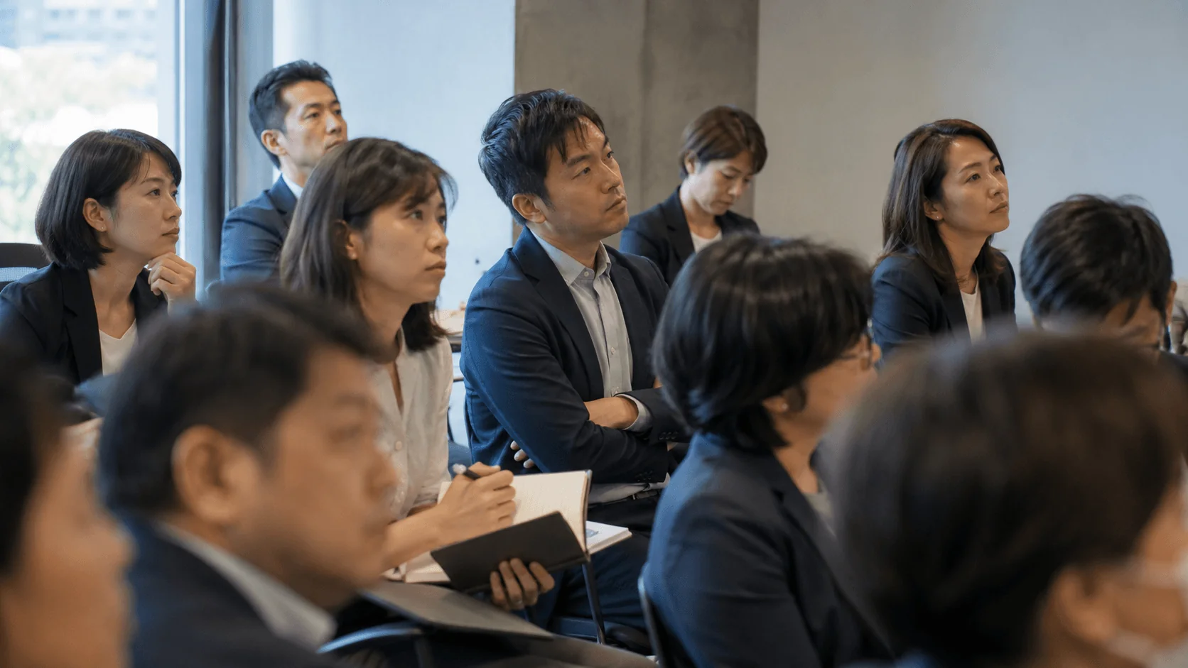 An attentive audience of Japanese business professionals at a Remark seminar, taking notes
