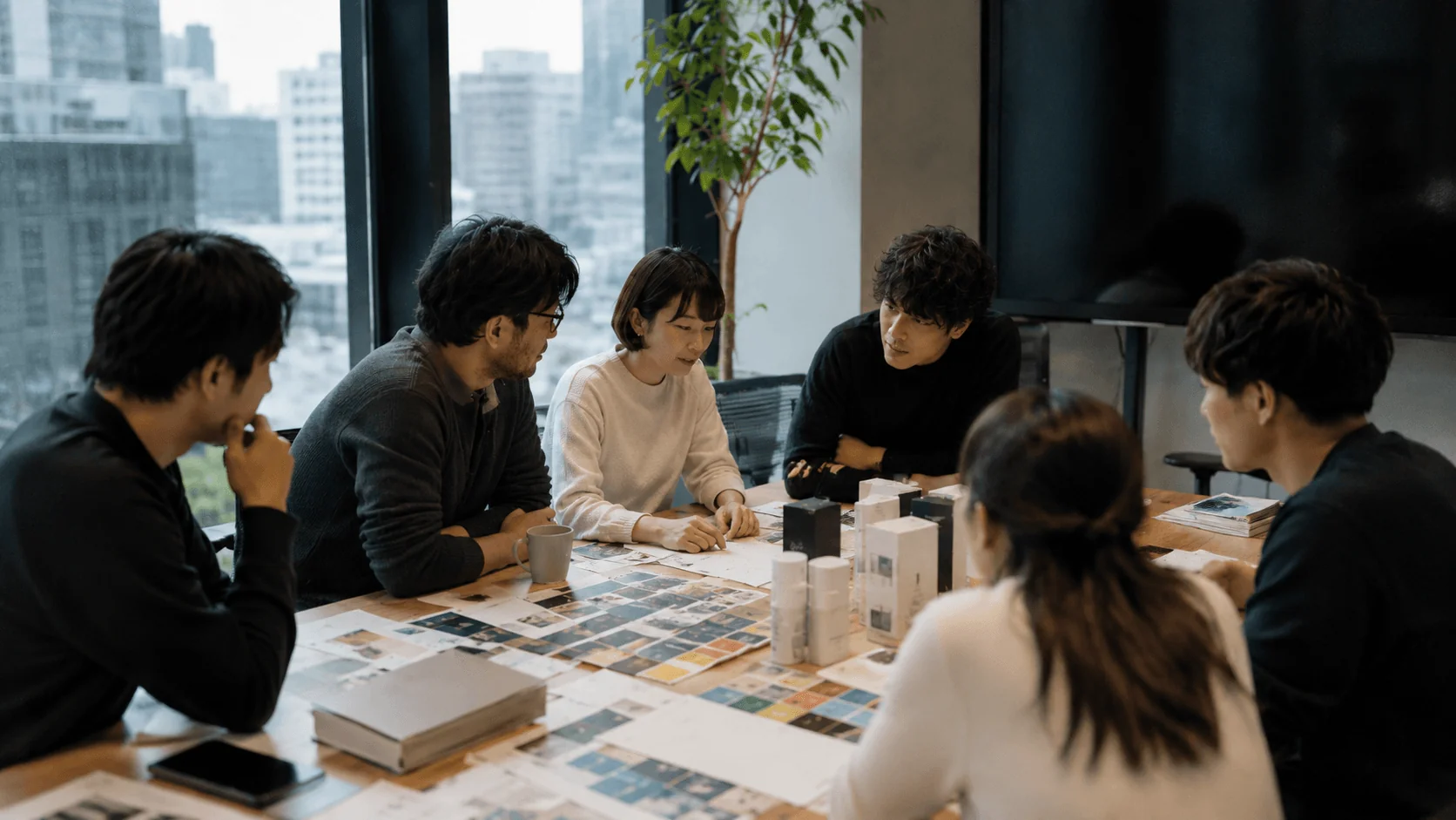 A Remark brand working session in Tokyo — a team reviewing packaging and printed materials around a table
